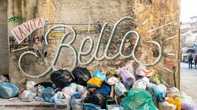 Algo huele mal - Huelga de limpieza en Madrid Basura sin recoger en la calle ante una pared con una pintada que dice "La Vita e Bella"